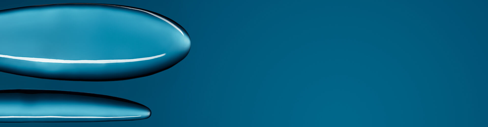 A close-up of smooth, shiny silicone surfaces against a blue background, resembling implant shapes.